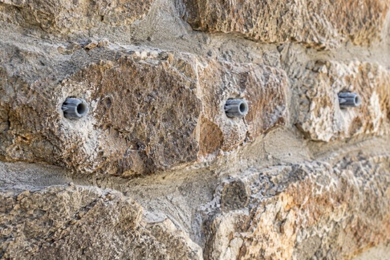 Muro de piedra con agujeros taladrados y tacos de plástico colocados
